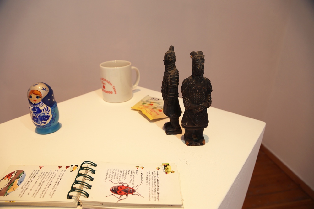 object: matryoshka doll (with a few inner dolls missing), a corporate coffee cup, two portions of tea bags, a hand book on insects/bugs and a pair of souvenir Terracotta Army soldiers